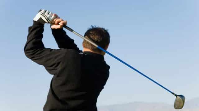 Golfer using an iron club to hit the ball